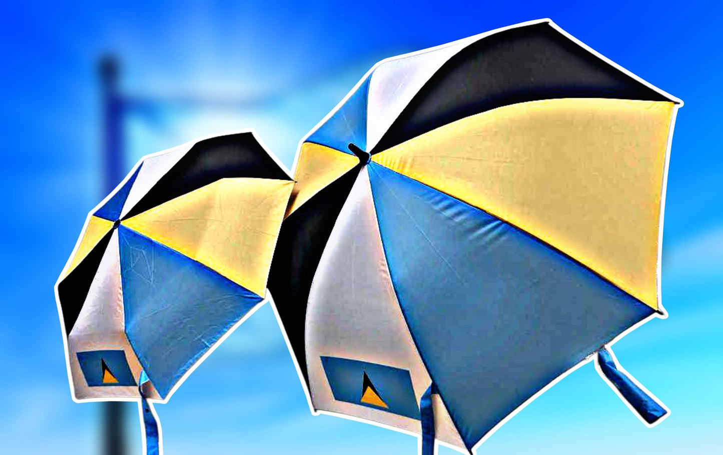 Two colorful St Lucia beach umbrellas featuring blue, black, and yellow panels, ideal for sunny beach days